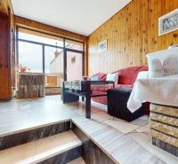 Living room in a family house with wooden paneled walls and tiled floor.