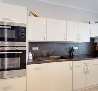 A kitchen in a family house with white cabinets, a sink, and built-in appliances.