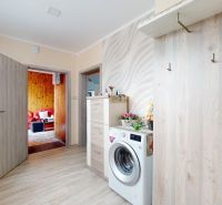 Interior of a family house with a washing machine, dresser, and wooden decor flooring.