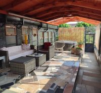 A glazed terrace of a family house with rattan furniture and a hot tub.