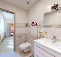 A bathroom in a family house with ceramic tiles and a wooden decor floor.