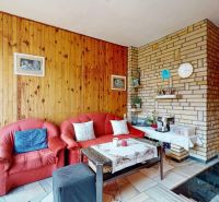 Living room with wooden paneling, fireplace, and red sofa set in a family house.