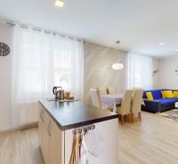 A kitchen and living room in a family house with a wooden decor floor and light furniture.