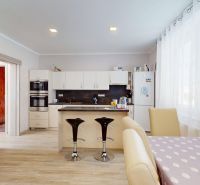 A kitchen in a family house with an island, two chairs, and a wooden decor floor.