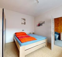 Bedroom in a family house with a bed, wardrobe, and wall decorations.