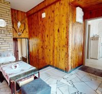 Interior of a family house with wooden paneling, a sofa, and a coffee maker on a stone wall.