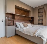 A bedroom in an apartment with modern cabinets and a wooden decor floor.