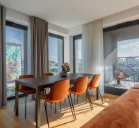 Dining area with orange chairs, wooden decor flooring, access to the balcony. Apartment construction.