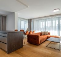 Living room with an orange sofa, wood-patterned floor, and a table in the living room.