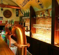 A bar counter in a gastro space with a brick wall and brass taps.