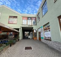 Commercial spaces in Topoľčany with an open passage and outdoor advertisements.