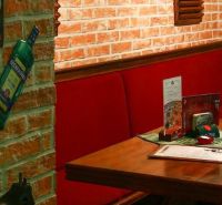 A brick wall and wooden furniture in the dining area with red seating add coziness.