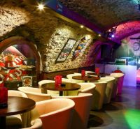 A bar in historical gastro premises with stone walls and a wooden decor floor.