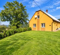 A family house on Košariská Street in Oščadnica surrounded by a large garden and trees.