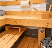 A sauna in a family house with wooden paneling and a stove with stones.