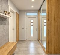 Interior of a family house with wooden decor and a large mirror in the hallway.