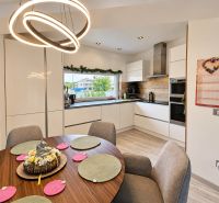 A kitchen in a family house with a dark table, modern lighting, and a floor with a wooden decor.
