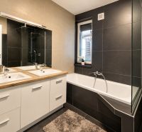 A bathroom in a family house with a double sink and a bathtub, light tiles.