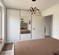 A bedroom in a family house with a large built-in wardrobe and a floor with a wooden decor.