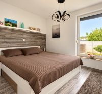 A bedroom with a brown bed, wooden paneling, and a wooden decor floor in a family house.