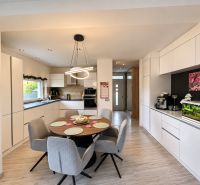 Interior of a family house with a kitchen, dining table, and wooden decor flooring.