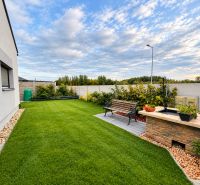 The garden of a family house in Mosonmagyaróvár with a bench and an outdoor grill on the lawn.