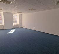Spacious offices with blue carpet and ceiling lights.
