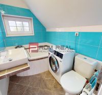 A bathroom in a 2-room apartment with a washing machine, a sink, and turquoise tiles.