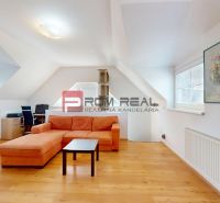 A bright living room with an orange sofa, a work corner, and a wooden decor floor.