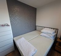 A bedroom in a studio apartment with a dark wall and a wooden decor floor.