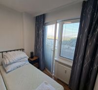 Bedroom space in a studio apartment with curtains and a window with a view.