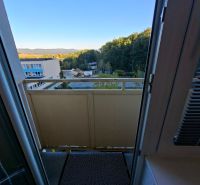 View from the balcony of a one-room apartment on Školská Street in Kanianka with a forest backdrop.