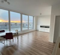 Living room with a dining table, large windows, and a wooden decor floor.