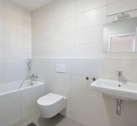Bathroom in a 3-room apartment with a bathtub, toilet, and sink, beige-colored tiles.