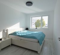 A bedroom with white furniture and a turquoise blanket in a 3-room apartment.