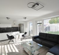 A bright living room with a kitchen in a 3-room apartment, sofa, dining table, wooden decor flooring.