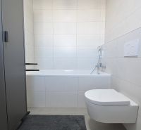 Bathroom with a bathtub and wall-mounted toilet in a 3-room apartment. Minimalist design.