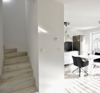 Interior of a 3-room apartment with a dining area, kitchen, and staircase with wooden decor.