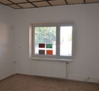 Offices with white walls and a floor with a wooden decor, a window with a radiator is visible.