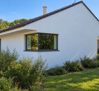 A family house in Ratnovce surrounded by greenery, with large windows and a simple white facade.