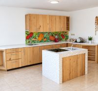 A kitchen in a family house with a kitchen unit and a colorful vegetable backsplash.
