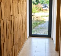 A hallway in a family house with wooden elements on the wall and glass doors.