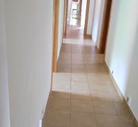 A hallway in a family house with tiles and white walls.