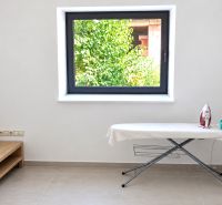 Ironing board with an iron in a room with a window and a mirror in a family house.