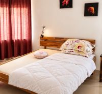 Bright bedroom with a bed, mirror, and red curtains in a family house.