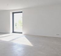 A spacious room in a family house with large windows and white walls.