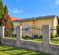A family house in Martovce with a garden surrounded by green trees and a fence.