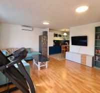 Living room in a family house with wood-patterned flooring, a sofa, and a television.