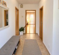 Hallway in a family house with tiles, a shoe bench, and a mirror.
