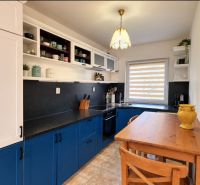 A kitchen in a family house with stylish blue cabinets and a cozy wooden table.